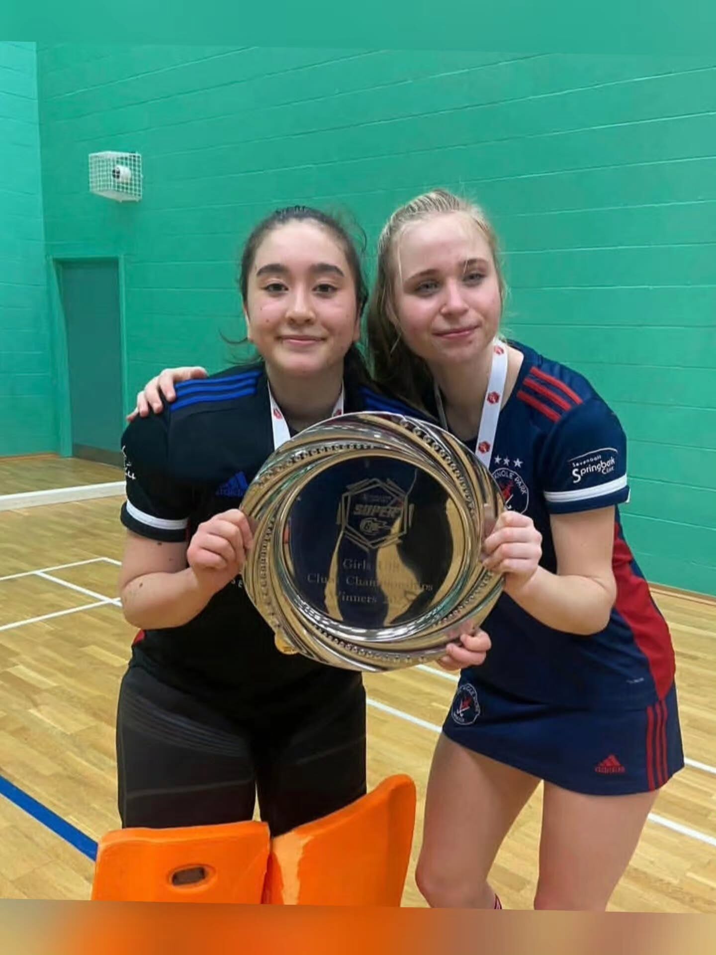 Two HC Knole Park players holding the Girls Club Championships Super 8s winners' plate