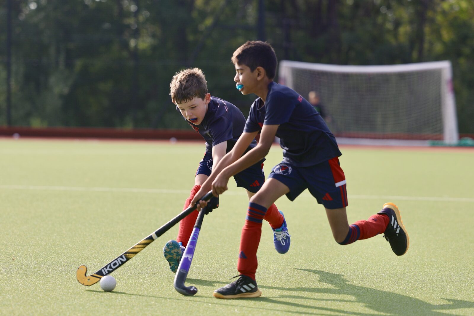 Sticks clash as two juniors in navy contest the ball