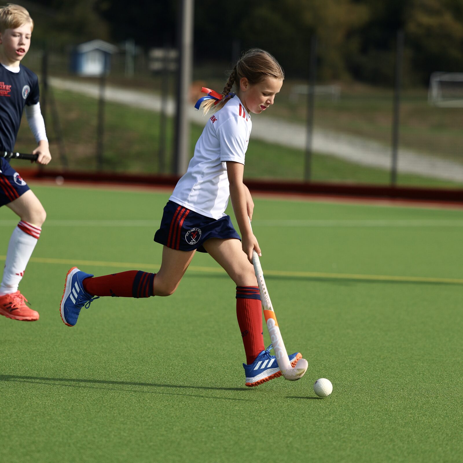 A girl in white drives the ball upfield