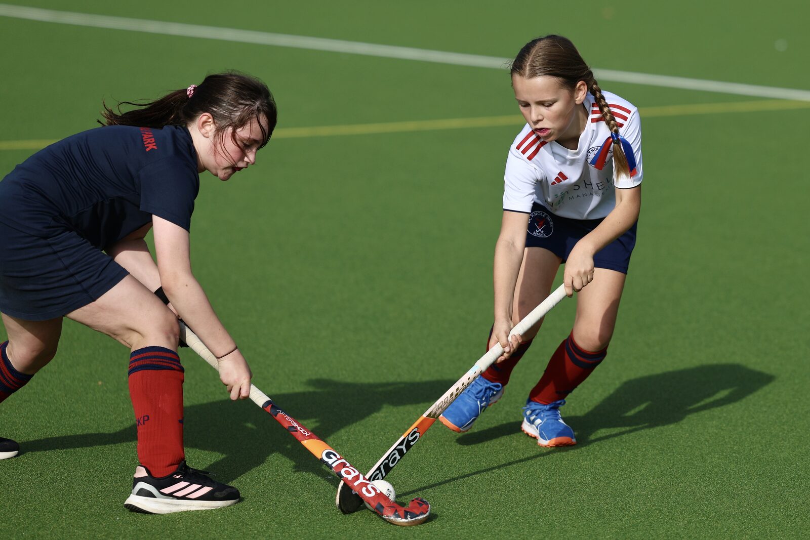 Two girls crouch low fighting for possession